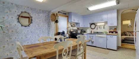 A cozy kitchen with a dining table, chairs, and a variety of kitchen appliances.