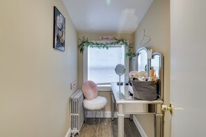Ein kleines Badezimmer mit Waschtisch, Heizkörper, einem flauschigen Hocker und einem Fenster mit Aussicht.