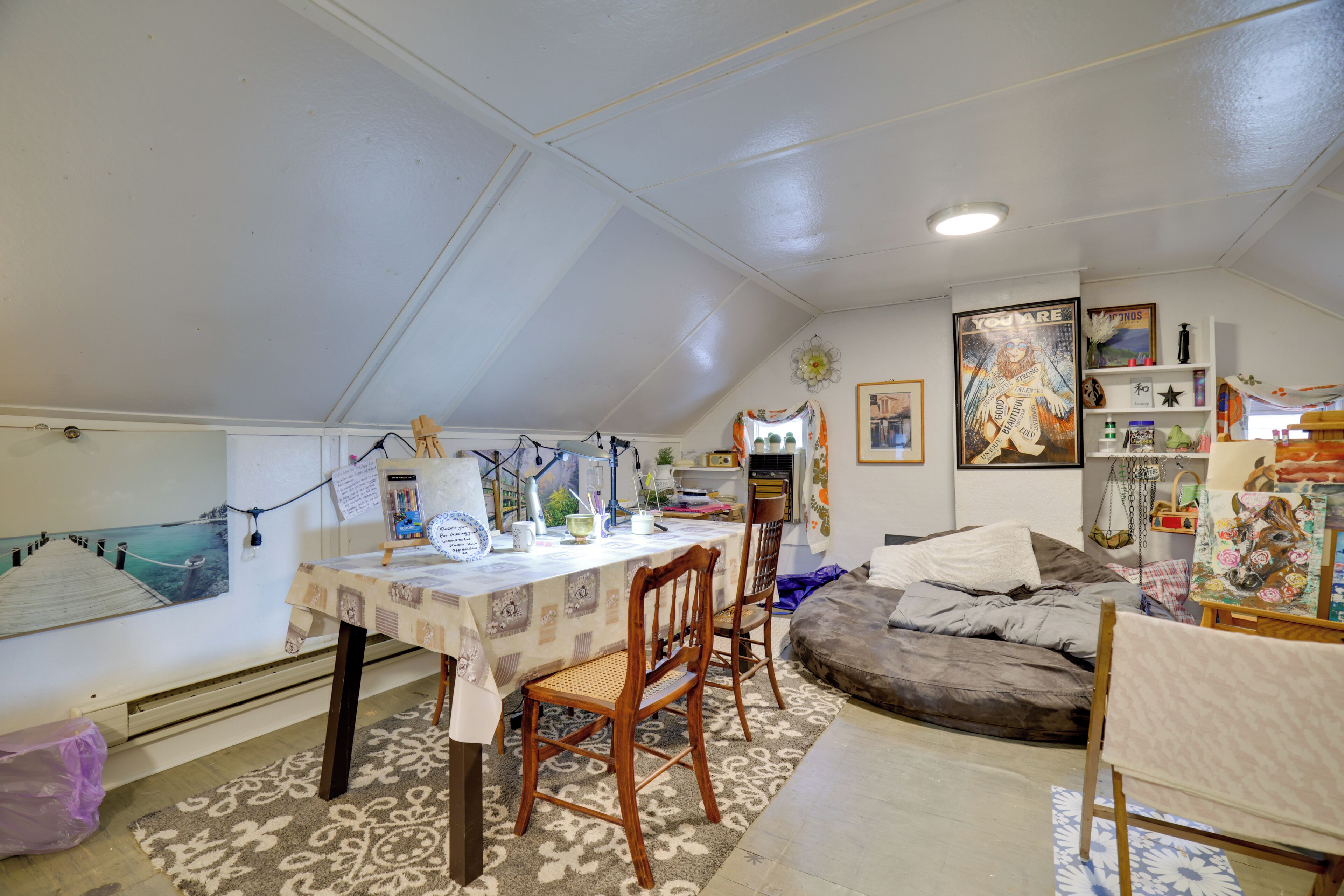 Acogedor cuarto ático con una mesa de comedor, sillas, un sofá y varias decoraciones.