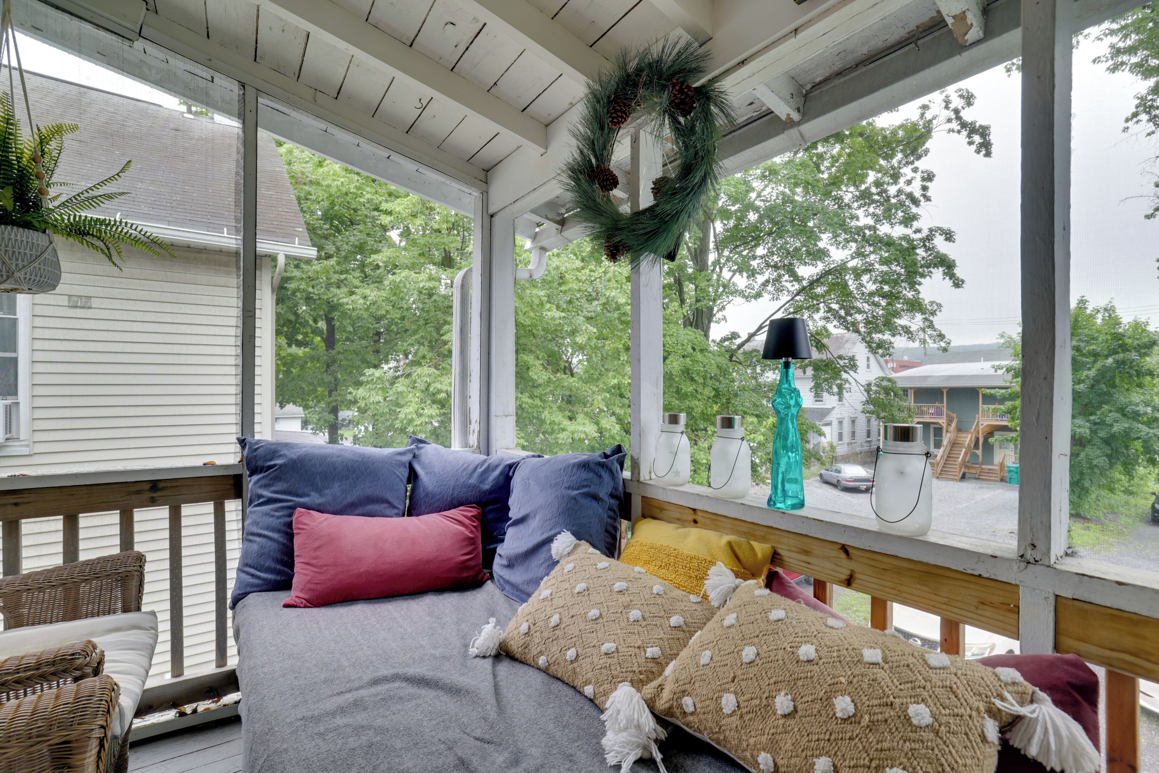A bedroom with a bed, pillows, a window, and a view of the outside.