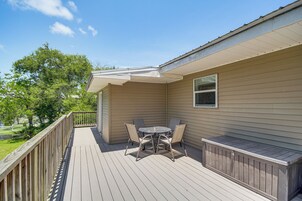 Un patio techado al aire libre con una mesa y sillas, una ventana y vistas a un paisaje verde.