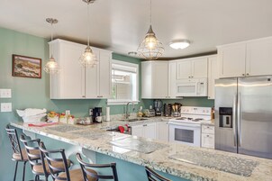 Una cocina moderna con gabinetes blancos, un refrigerador de acero inoxidable, un horno empotrado y una encimera de granito.