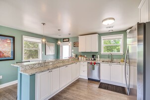 Una cocina moderna con gabinetes blancos, encimeras de granito y electrodomésticos de acero inoxidable.