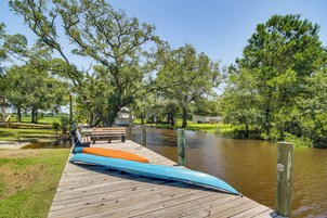 A wooden dock with canoes, a picnic table, and a river.