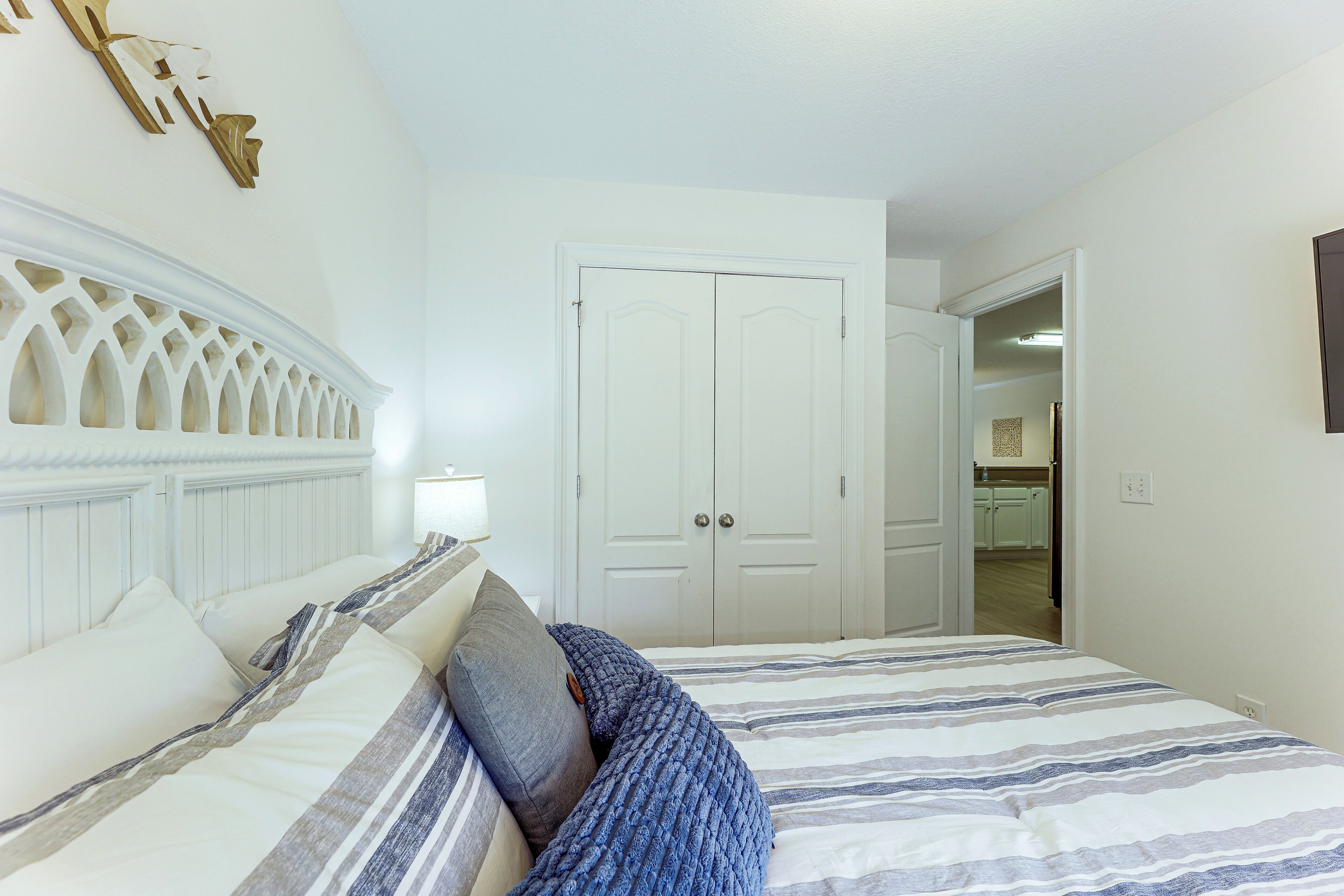 Un dormitorio con cama, mesita de noche, lámpara y armario.