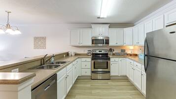 A modern kitchen with white cabinets, stainless steel appliances, and a granite countertop.