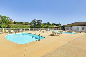 A swimming pool with lounge chairs and a covered seating area, surrounded by a fence and trees in the background. - Lake Martin Condo Getaway With Pool! (Alexander City)