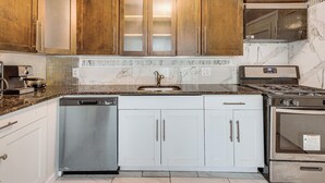 Una cocina con lavavajillas, estufa y armarios blancos.