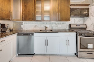 A kitchen with a dishwasher, stove, and white cabinets.