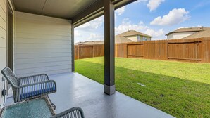 Ein überdachter Patio-Bereich mit zwei Korbstühlen und einem Betonboden.