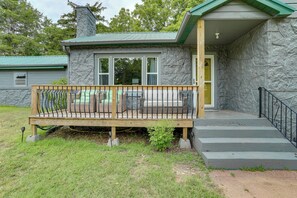 A stone house with a wooden deck, a front door, and a staircase leading to the entrance. - Peaceful Lake Getaway Near Bull Shoals Marina (Diamond City)