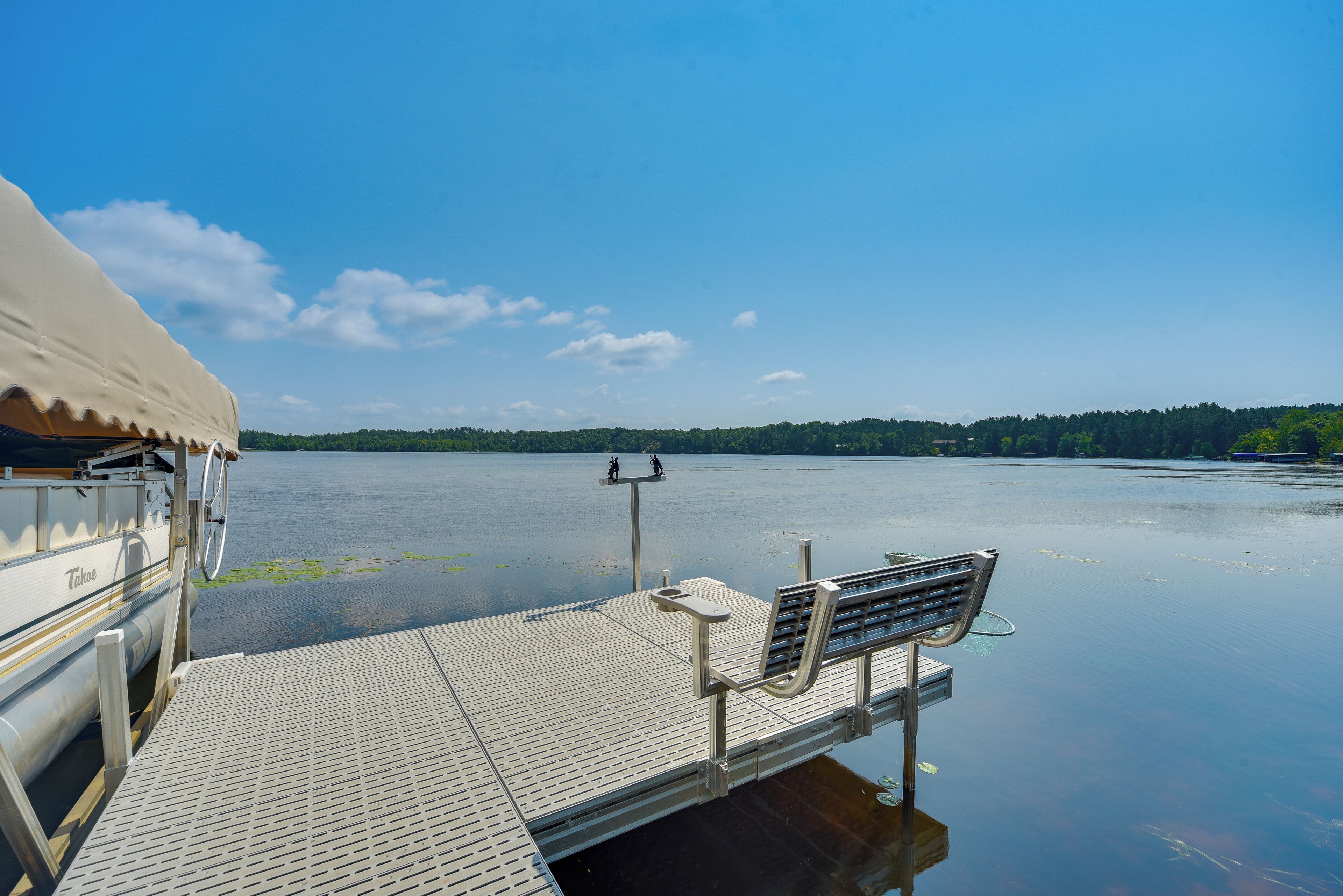 Une jetée s’avançant dans un lac paisible, avec un banc et un espace abrité sur la gauche.