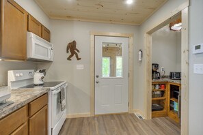 A kitchen with wooden cabinets, a white microwave, a stove, and a coffee maker.