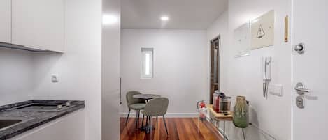 A modern kitchen with a marble countertop, a dining area with two chairs, and a wooden floor.