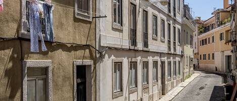 Uma rua de calçada estreita, ladeada por edifícios históricos com várias janelas e varandas.