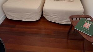 Ein kleiner, gemütlicher Raum mit zwei beigen Sesseln, einem Holzstuhl und einem Tisch mit einem Buch.
