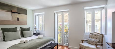 Una camera da letto con un letto, una sedia, una scrivania e un quadro appeso al muro.