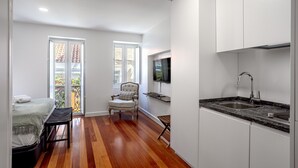 Una cocina compacta con televisión integrada, un lavamanos y un comedor con una silla.