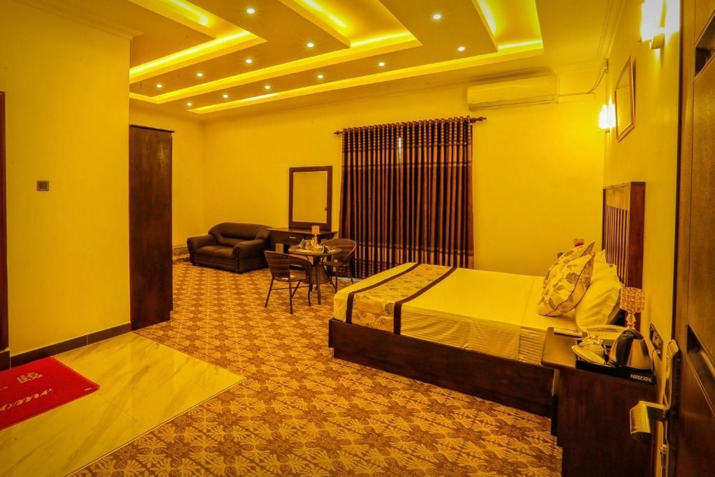 A hotel room with a bed, a desk, a chair, and a sofa.