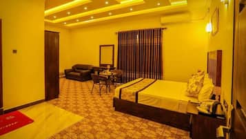 A hotel room with a bed, a desk, a chair, and a sofa.