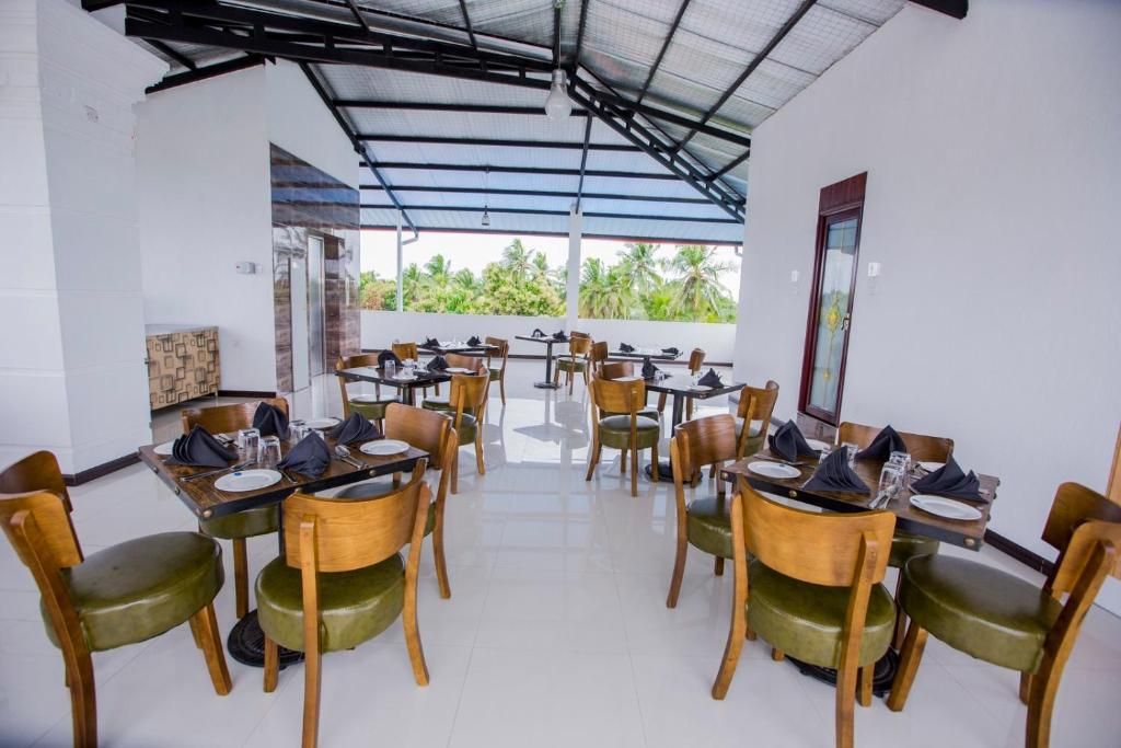 Un restaurant doté de nombreuses tables et chaises, d’un plafond en verre et offrant une vue sur la verdure environnante.