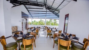Un restaurante con varias mesas y sillas, techo de cristal y vistas a zonas verdes.