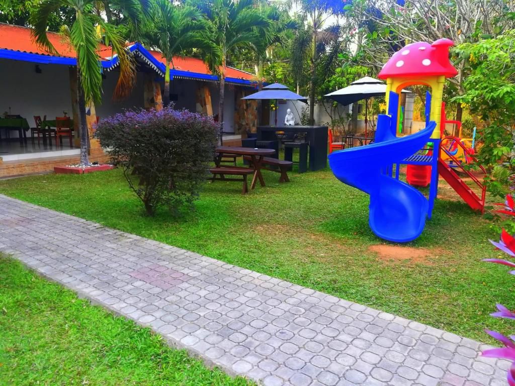 Zona de juegos infantiles con tobogán, mesas de picnic y un área de descanso cubierta.