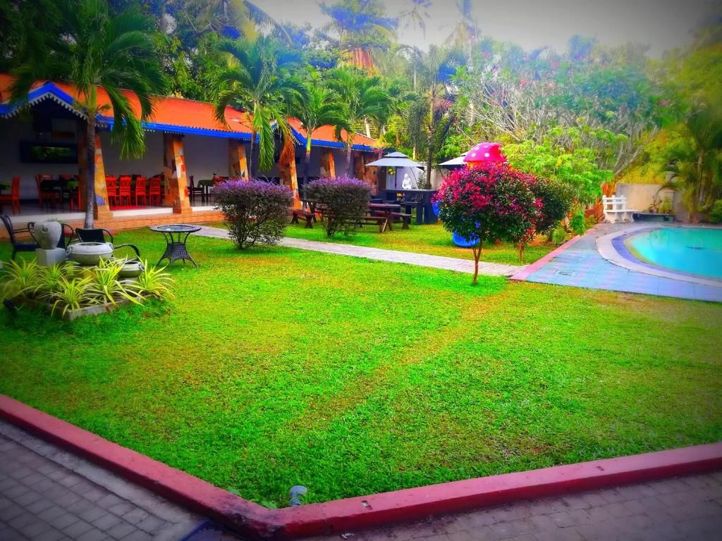 A well-maintained garden with a pool, outdoor seating, and a building with a red roof.