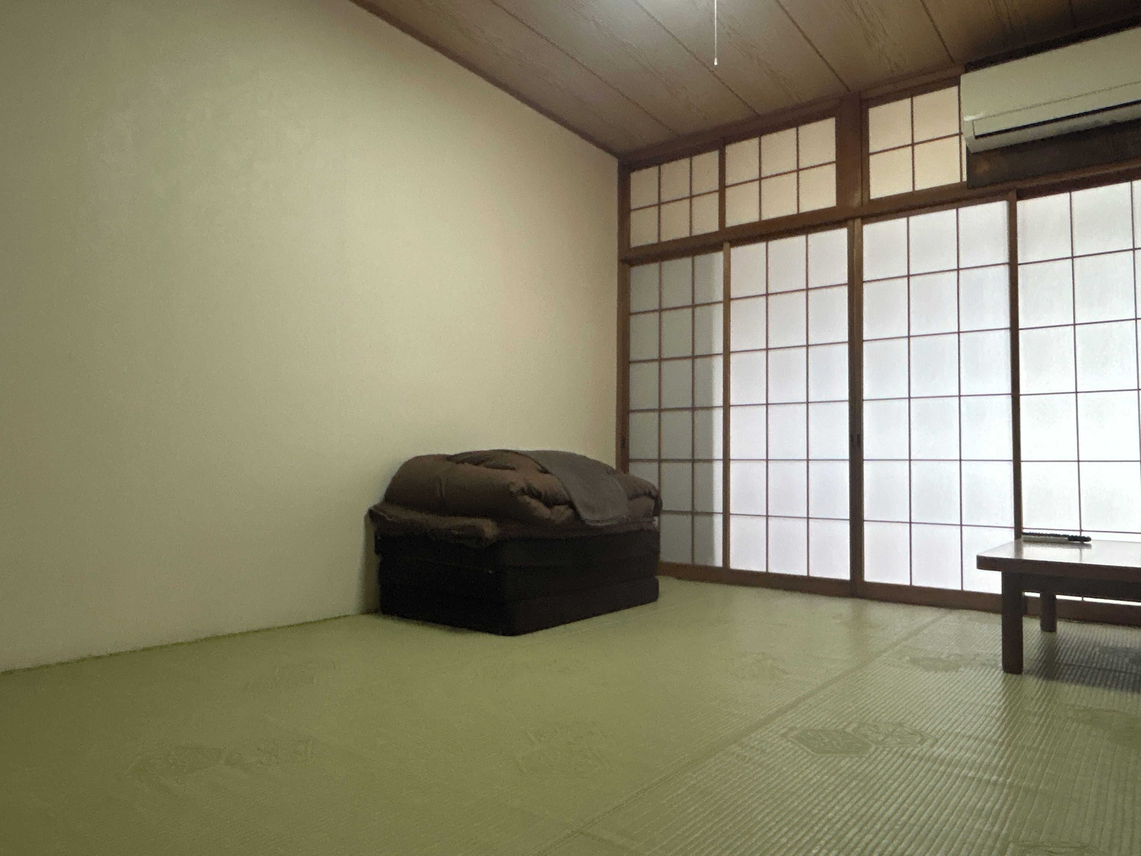 A room with tatami flooring, a low wooden table, and a cushion on the floor.