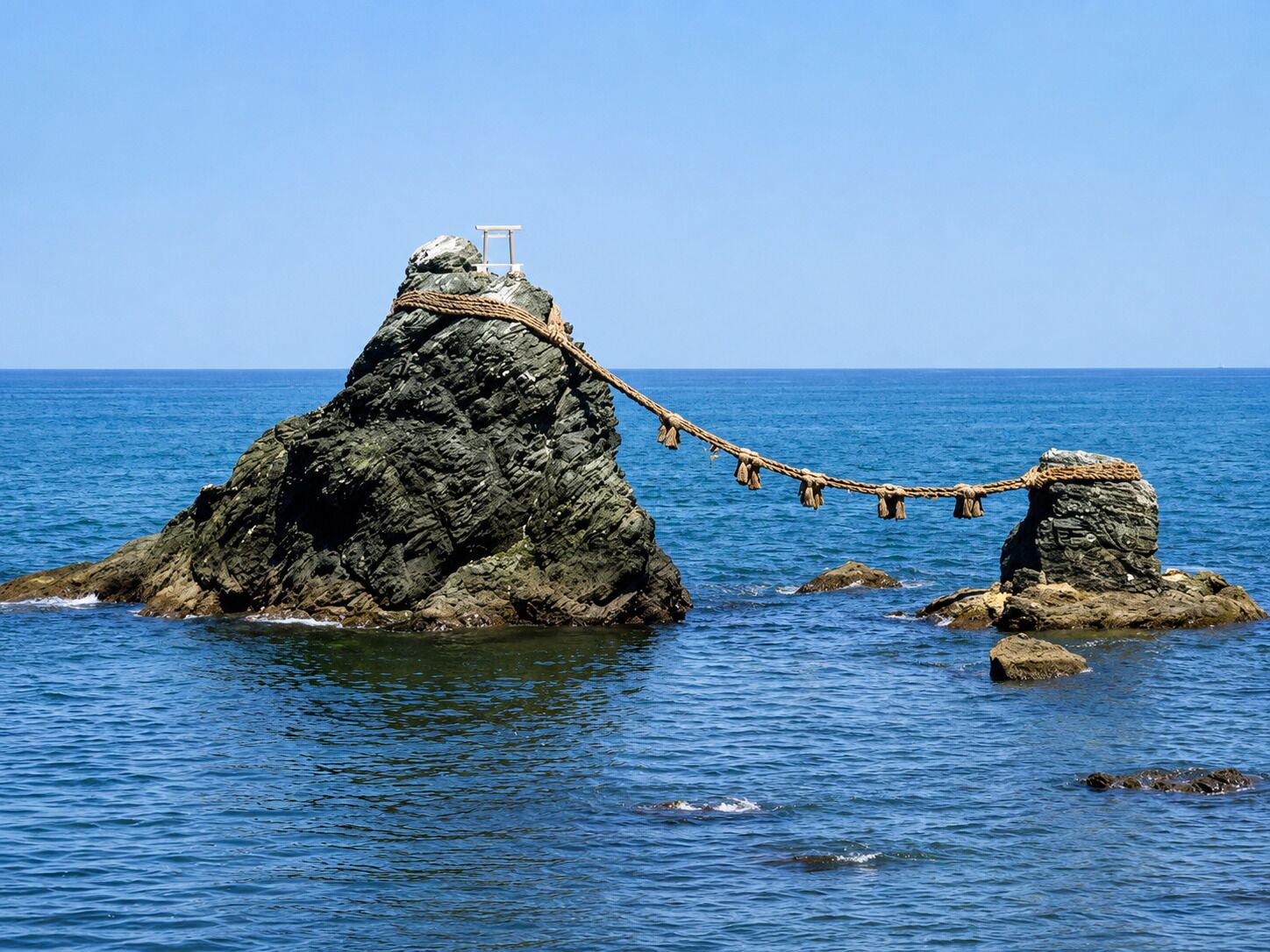 A rocky island with a rope bridge and a small structure on top.