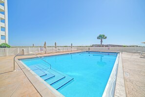 A swimming pool with a clear blue water, surrounded by a white fence, and a palm tree in the background. - Family Friendly Gulf Front Condo at Regency Towers with Pool & Tennis (Pensacola Beach)