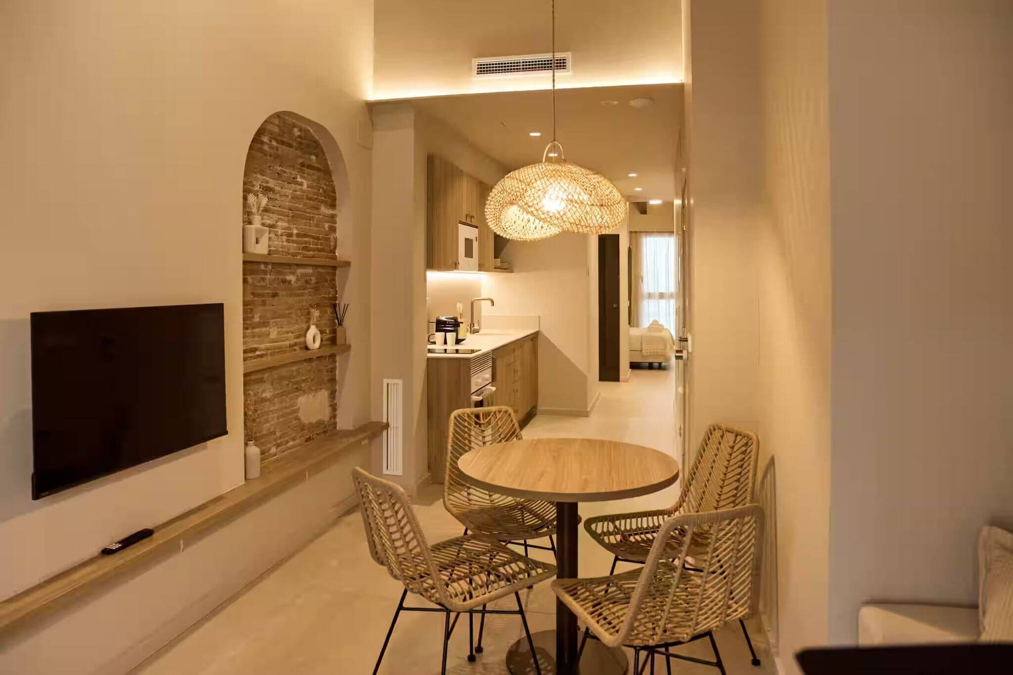 Un comedor moderno con una mesa redonda y sillas de mimbre, un televisor de pantalla plana en la pared y una pared de acento de piedra.