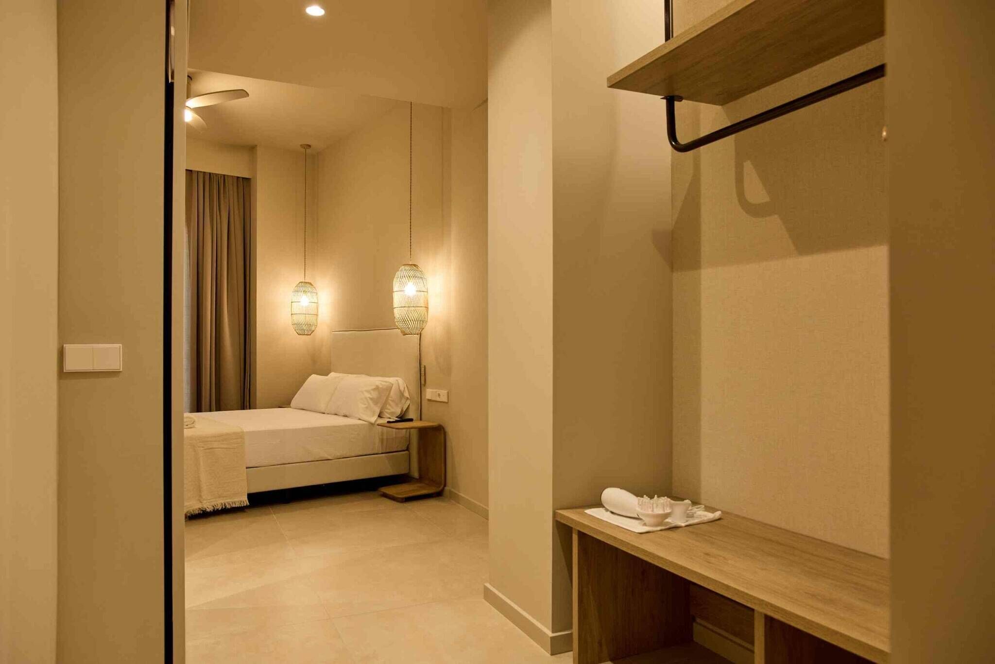 Ein Hotelzimmer mit einem Bett, Nachttischlampen, einer Holzbank und einem kleinen Tisch mit Toilettenartikeln.