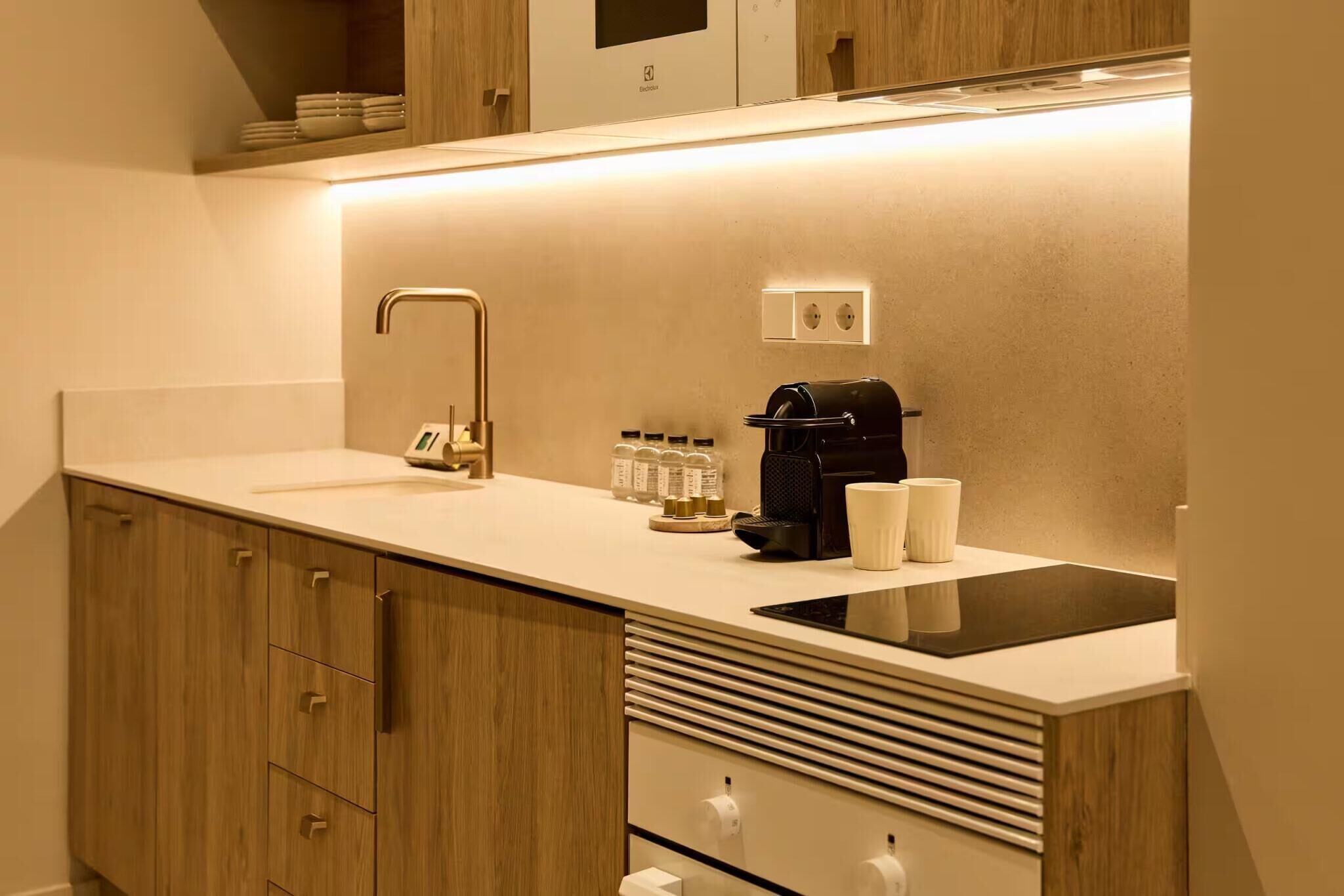 Una cocina moderna con estufa integrada, cafetera y pileta.