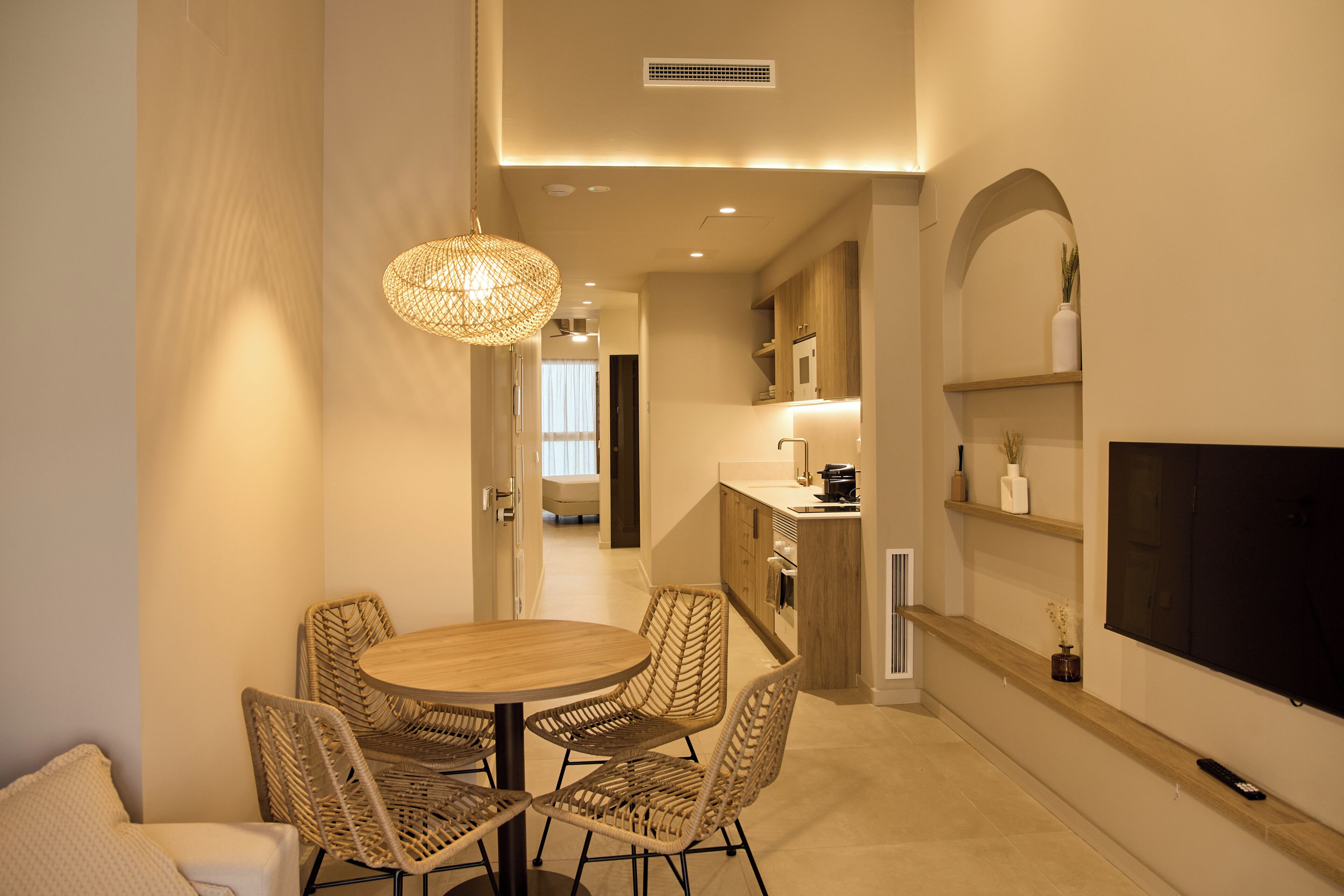 Una cocina moderna con zona de comedor, que incluye una mesa redonda y sillas de mimbre.