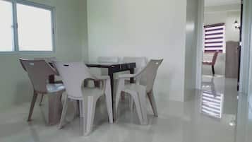 A dining area with a table and chairs, a window, and a door leading to another room.