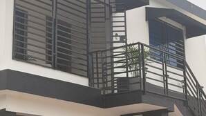 A two-story building with a balcony, a staircase, and a garage. - Modern apartment stay in Santo Domingo (Santo Domingo)