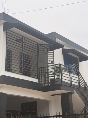 Ein zweistöckiges Gebäude mit Balkon, Treppe und Garage.