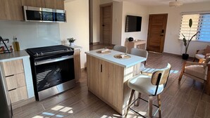 A modern kitchen with a built-in oven, a dining area with a central island, and a seating area with a sofa and chairs. - Modern apartment stay in Santo Domingo (Santo Domingo)