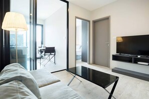 A modern living room with a glass coffee table, a sofa, a TV, and a lamp. - Pattaya Central Excellent 1 Bed Room Excellent Location (Pattaya)