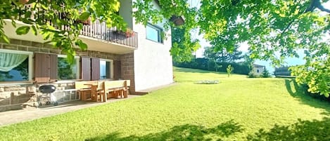 A two-story house with a balcony, a barbecue grill, and a well-maintained lawn.