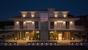 A two-story hotel with a central entrance, balconies, and outdoor seating areas. - TubHotel (Grottazzolina)