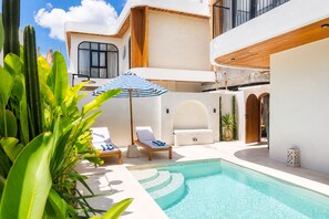A modern poolside area with lounge chairs, a pool, and a wooden deck. - 2BR Private Pool Villa Walk to Pererenan Beach and Cafes (Mengwi)