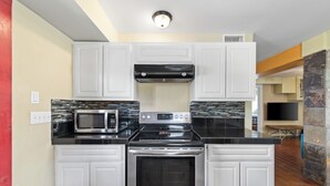 A compact kitchen with white cabinets, a microwave, a stove, and an oven. - Spacious Beach House w/Fenced Yard, Firepit, Patio & Walk to Beach! (South Padre Island)