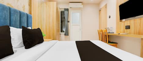 A hotel room with a bed, a desk, a chair, a TV, and a bathroom door.