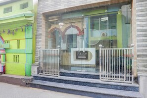 A building with a glass entrance, metal gates, and a sign indicating it is company-serviced.