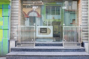 A building entrance with a glass door, metal gates, and a sign indicating 'Collection'.