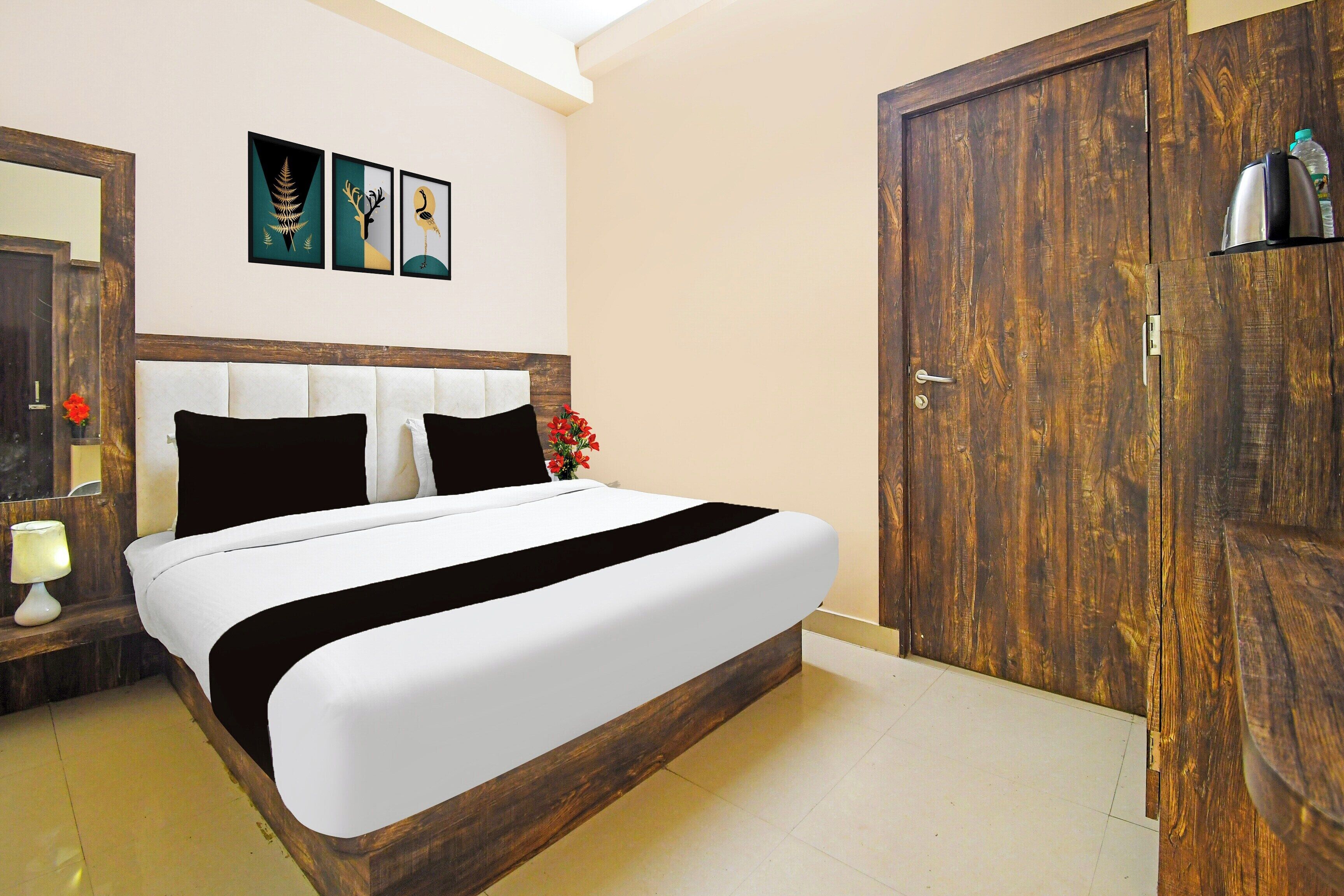 A room with a bed, a wooden door, and a wall with three framed pictures.