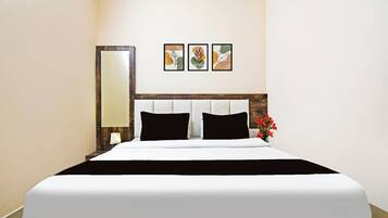 Une chambre d’hôtel avec un grand lit, une tête de lit en bois et trois œuvres d’art encadrées accrochées au mur.