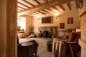 A cozy living room with a fireplace, wooden beams, and comfortable seating. - Boutique Cotswolds Cottage near Soho Farmhouse (Duns Tew)